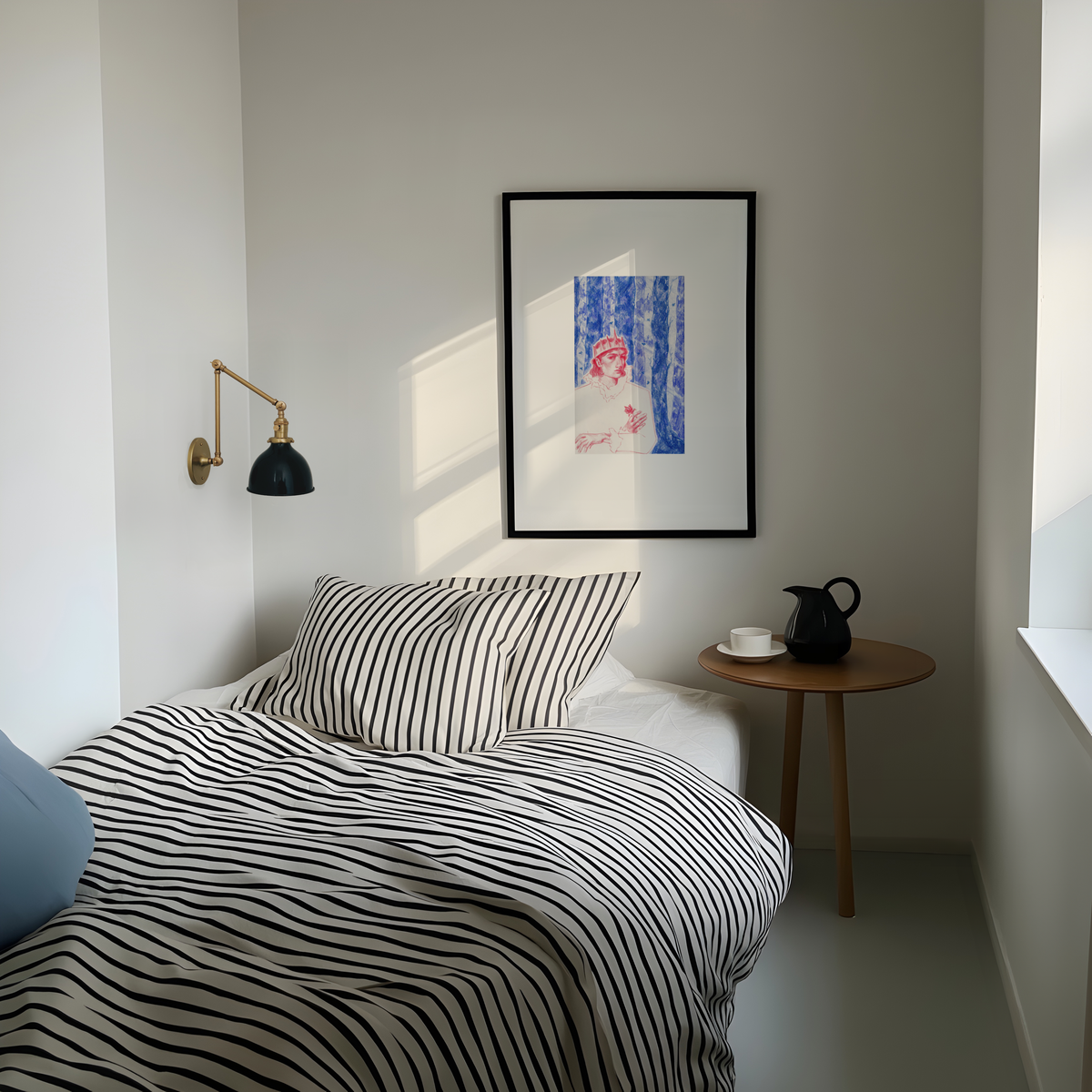 A styled bedroom corner featuring a bed with black and white striped bedding, a matching striped pillow, a small wooden side table with a black teapot, a black wall sconce, and a framed art print on the wall.